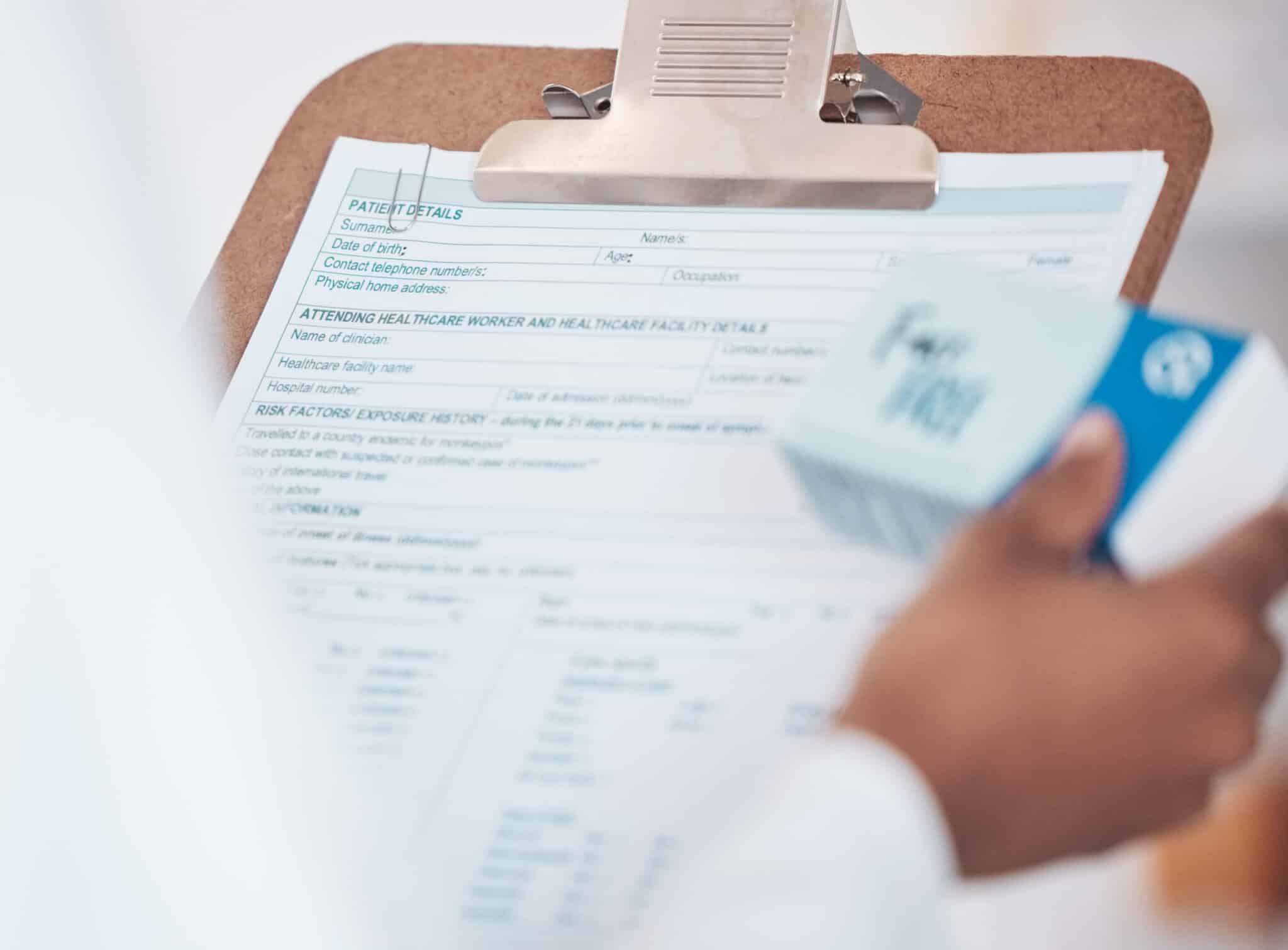 Pharmacist holding a medication box while reviewing a patient safety checklist form