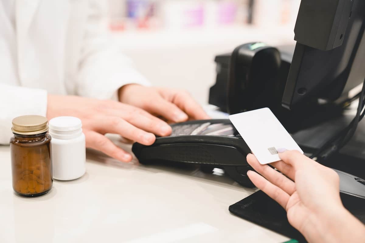 Person making a wireless payment with a credit card at a pharmacy counter.