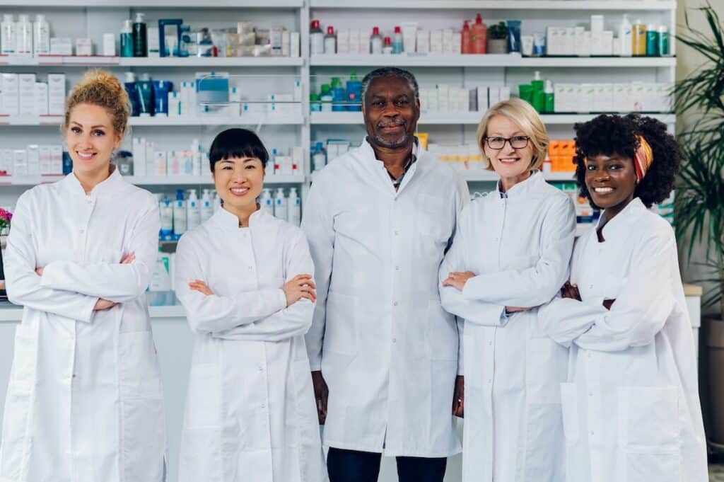 Group of multicultural professional pharmacists confidently standing in a pharmacy shop.